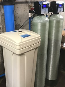 A water softener system installed in a basement utility room